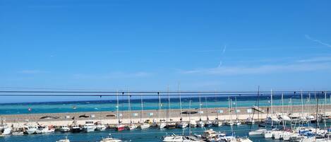 Un port de plaisance où de nombreux bateaux sont amarrés, un ciel dégagé et une mer calme.