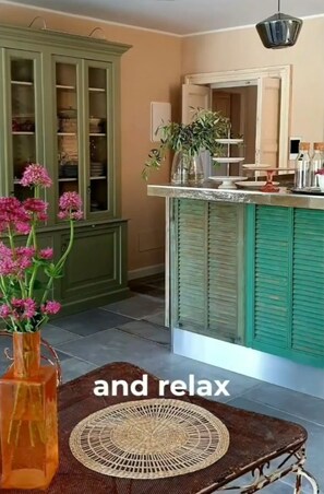 A kitchen with green cabinets, a marble countertop, and a hanging light fixture.