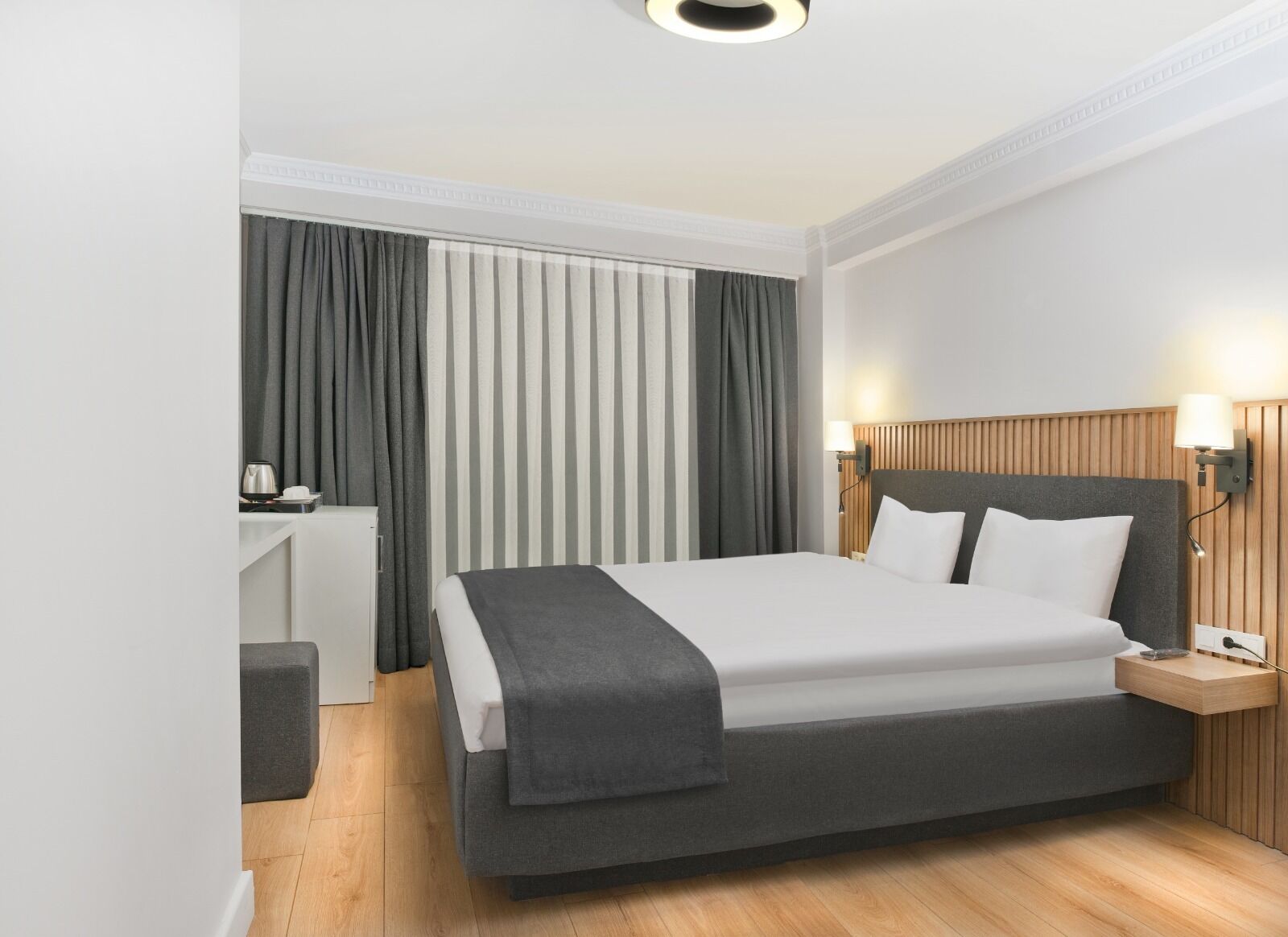 A modern hotel room with a large bed, a desk, and a chair.