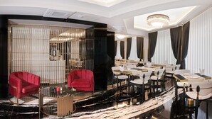 A modern interior with a seating area featuring red chairs, a dining section with tables, and a chandelier. - Silvana Hotel (Istanbul)