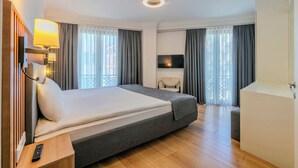 A modern hotel room with a large bed, a flat-screen TV, a bedside table with a remote control, and a balcony with curtains. - Silvana Hotel (Istanbul)