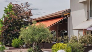 Une cour avec des sièges extérieurs, un bâtiment doté d’un toit en tuiles et diverses plantes.