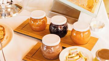 Une table de buffet proposant une variété d’aliments, notamment des pots de miel, des pâtisseries et un présentoir avec des rayons de miel.