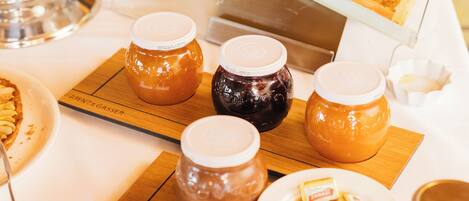 A buffet table with various food items, including honey jars, pastries, and a honeycomb display.