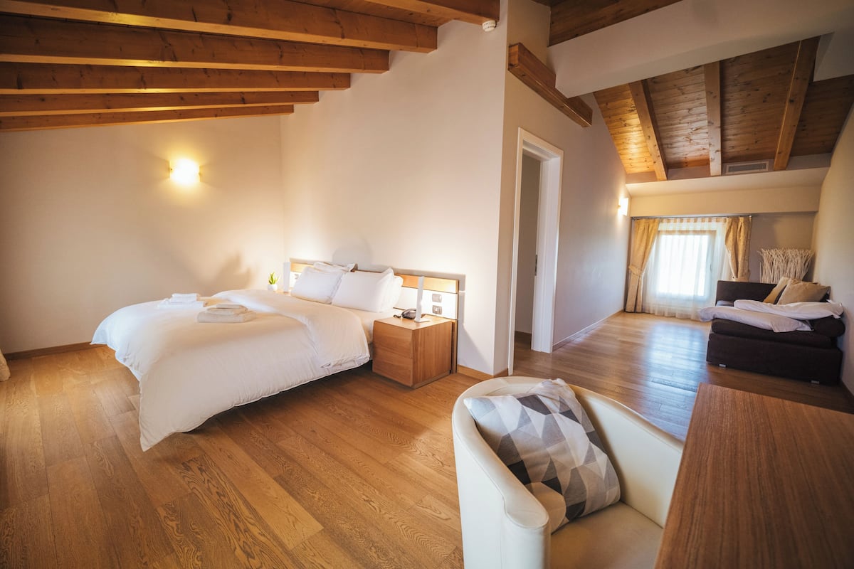 Ein Schlafzimmer mit zwei Betten, Holzböden, einem Sofa und einer Holzbalkendecke.