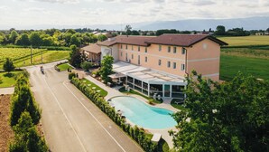 Un grand bâtiment doté d’une piscine, entouré de verdure et de champs.