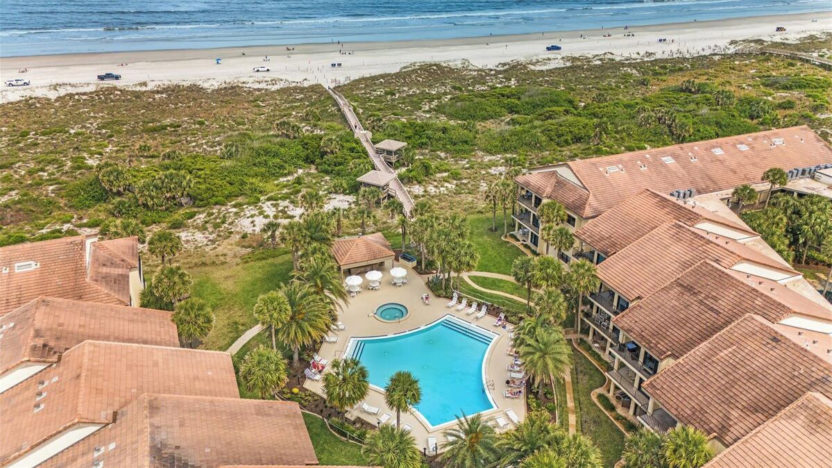 A resort with a swimming pool, beach access, and multiple buildings with red-tiled roofs.
