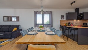 A modern kitchen with a wooden island, bar stools, and a dining table set for six. - Villa Cesarica (Polaca)