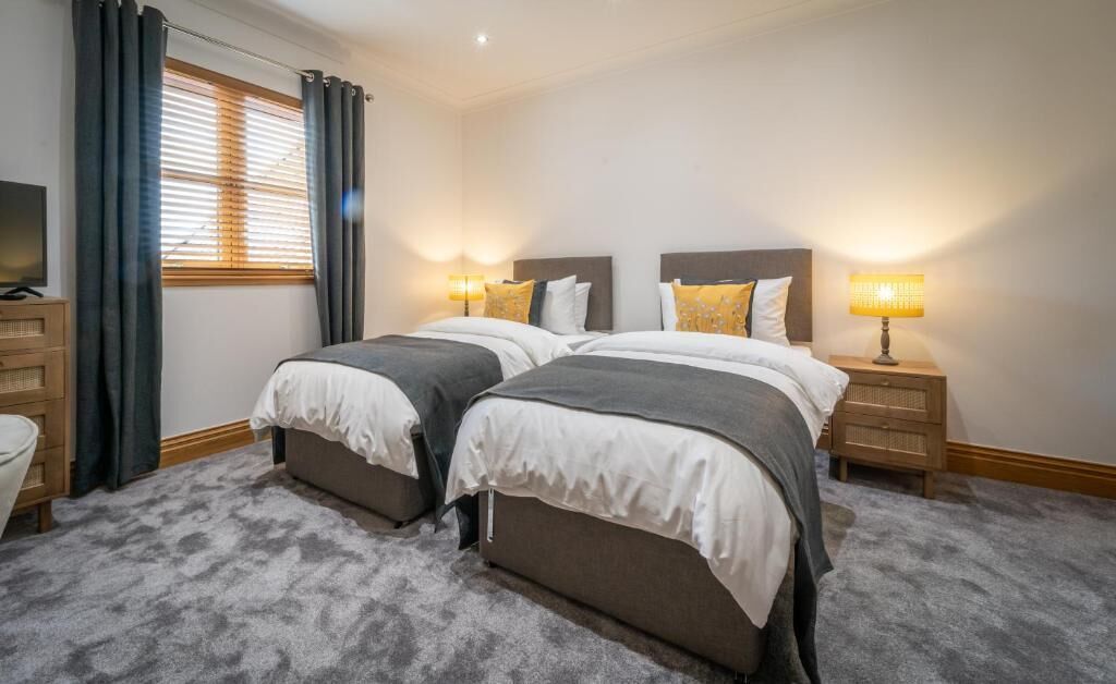 Une chambre avec un lit double, deux tables de chevet, une télévision et une fenêtre avec des rideaux.