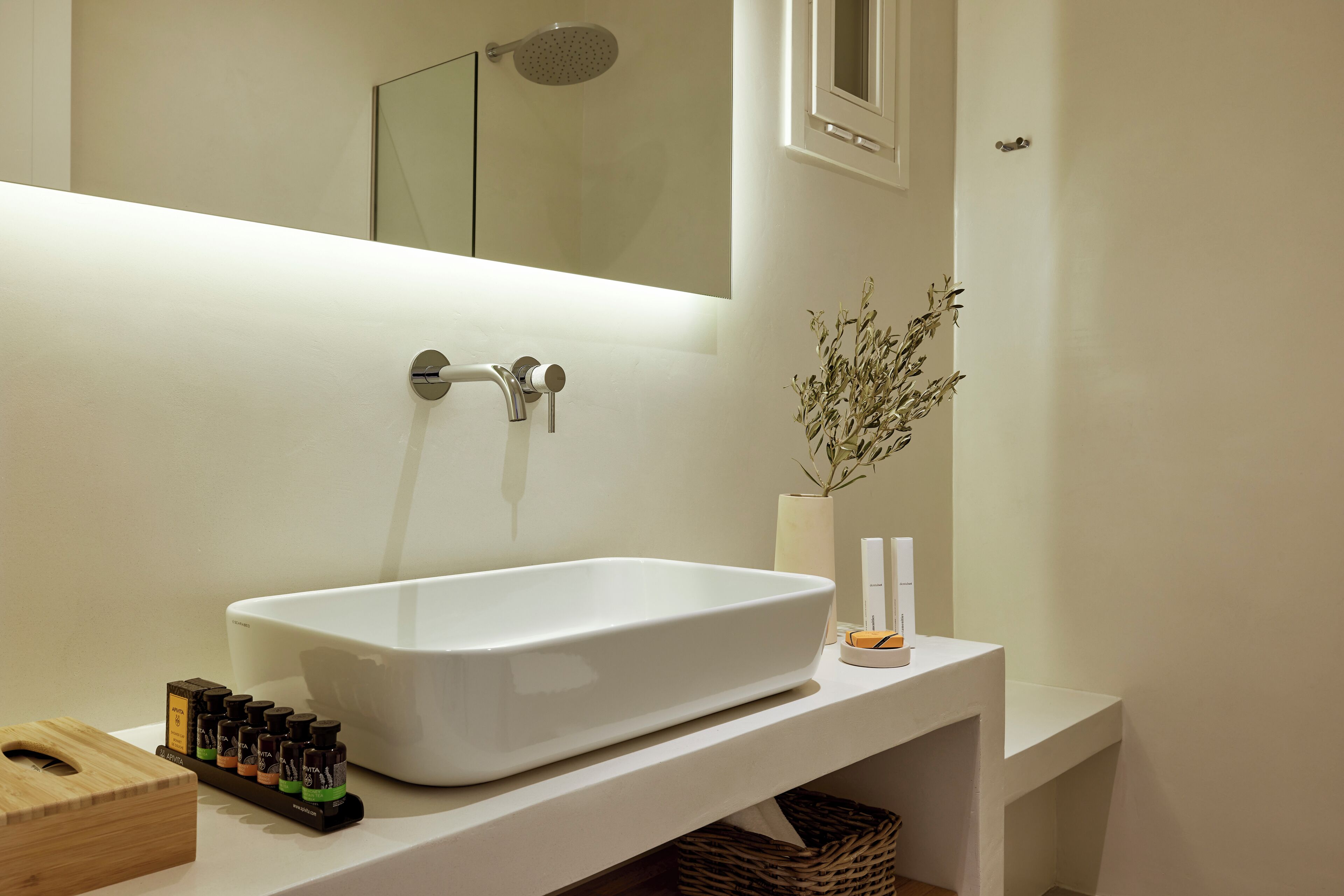 A modern bathroom with a white freestanding bathtub, a mirror above it, and a small potted plant on the counter.