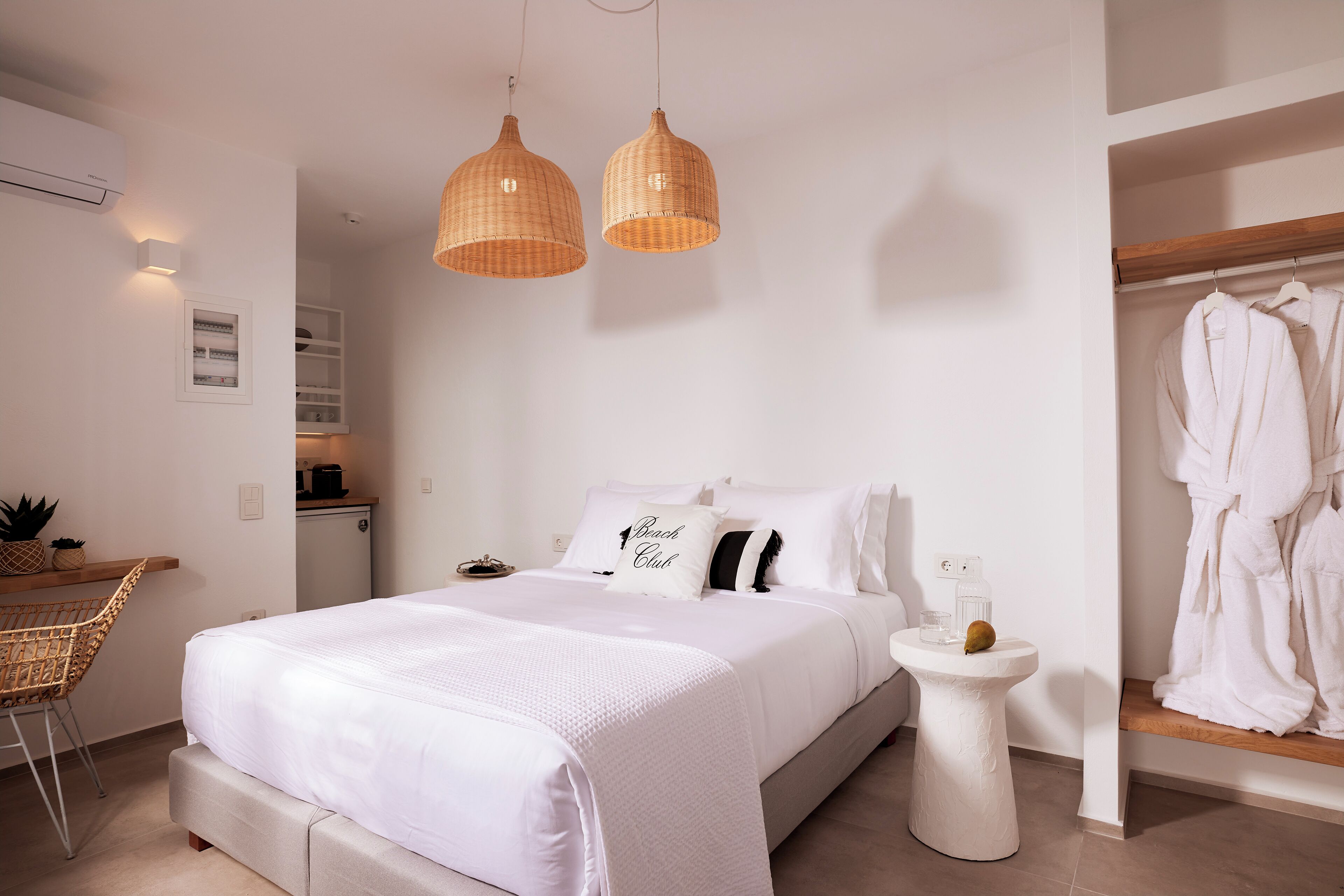 A neatly arranged bedroom with a bed, bedside table, and a hanging robe rack.