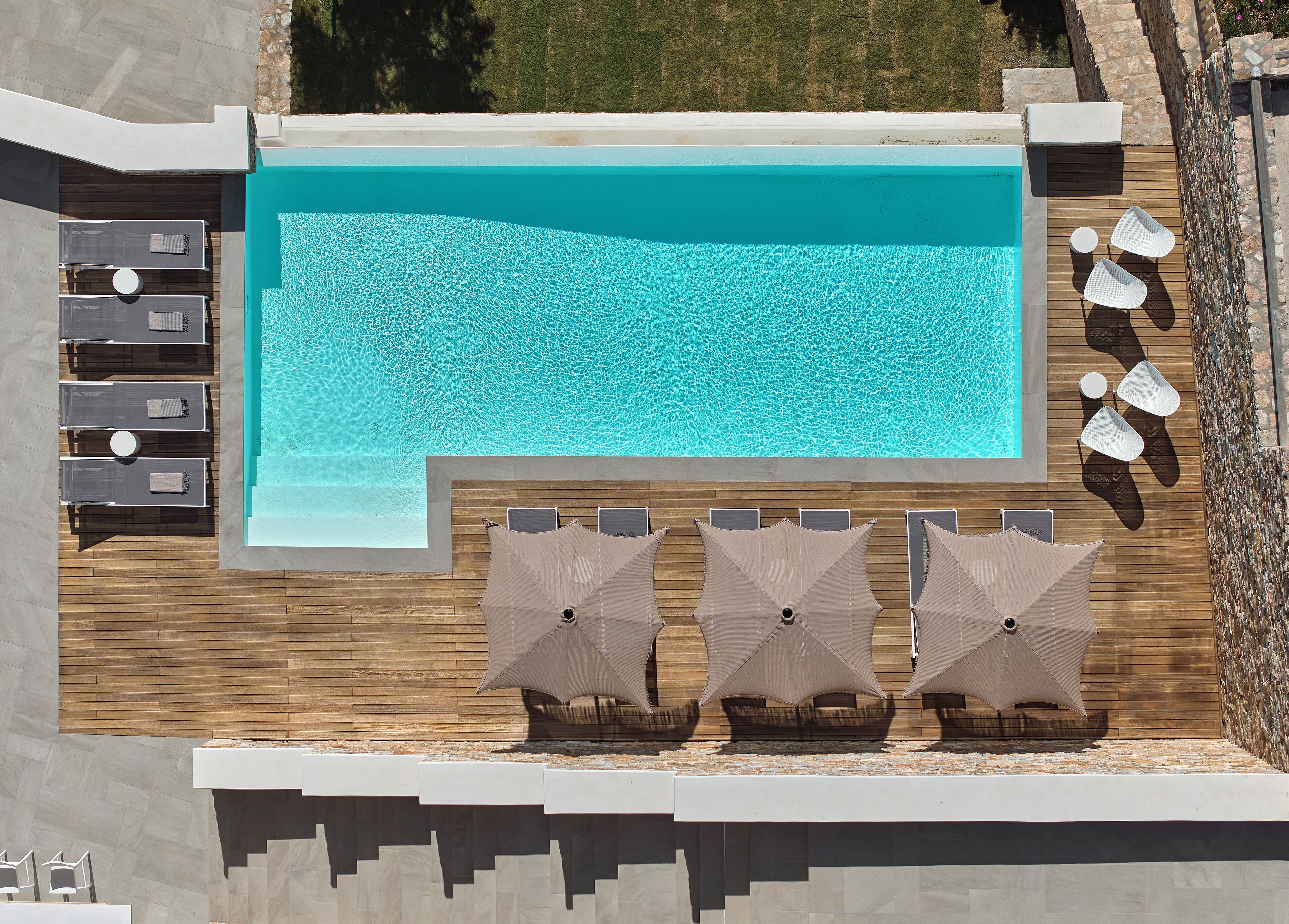 A rooftop pool with clear blue water, surrounded by wooden deck and lounge chairs.
