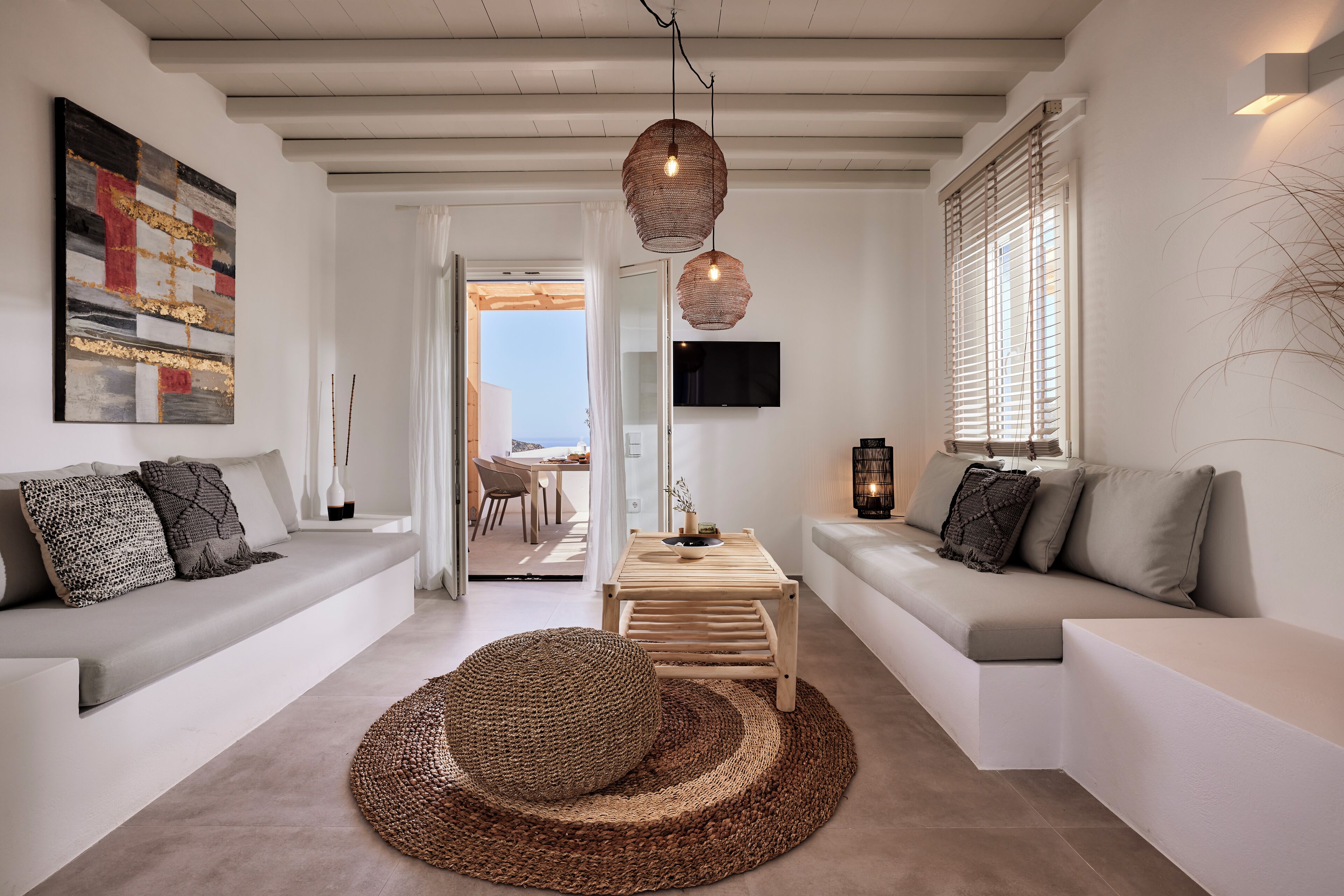 Un salon moderne avec un canapé, un tapis rond en fibres naturelles et une table basse en bois.