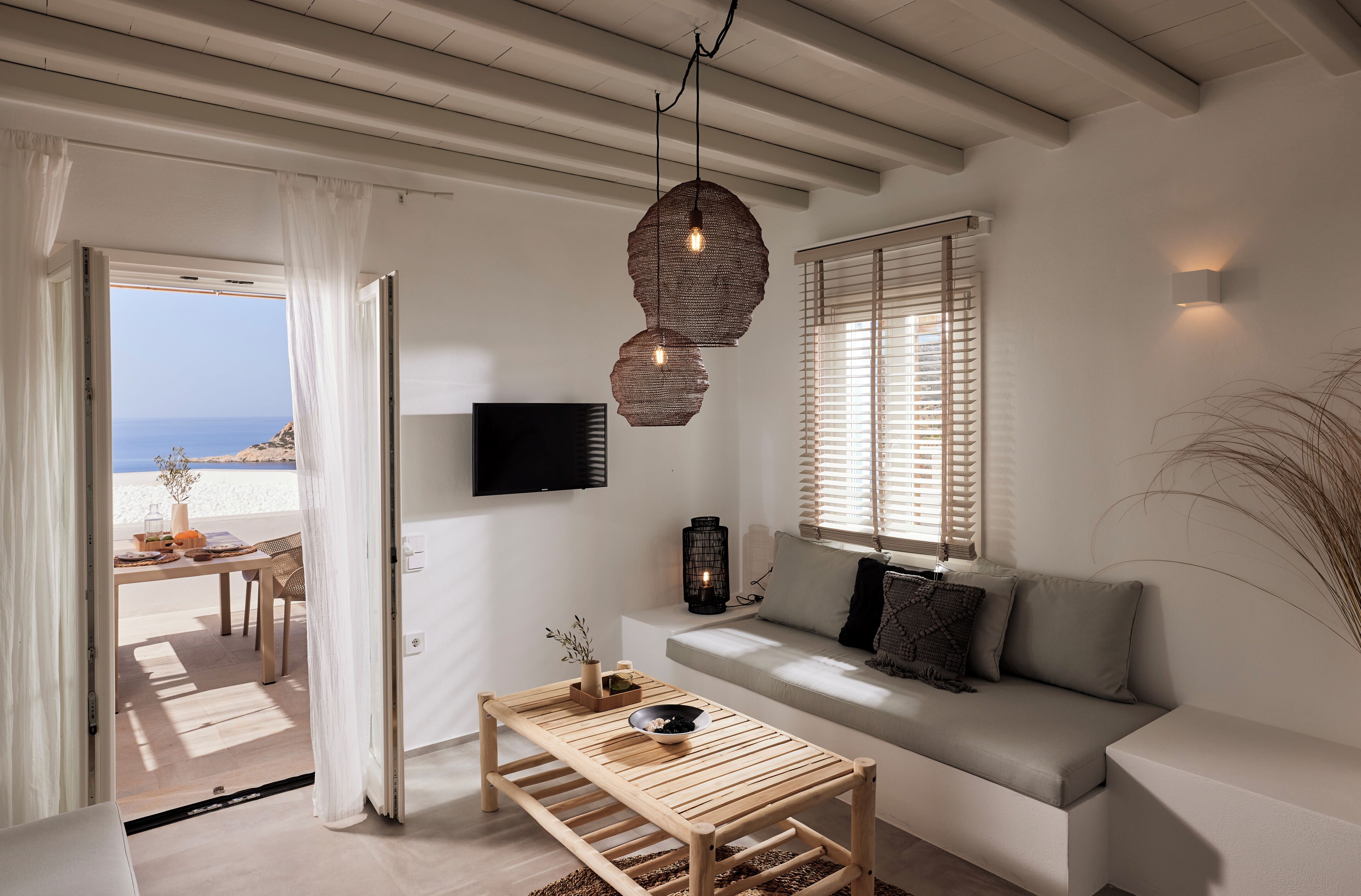 A modern living room with a wooden coffee table, a sofa, and a TV mounted on the wall.