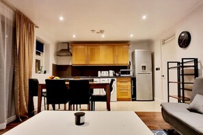 Cozy living space with a kitchen area, dining table, and sofa.