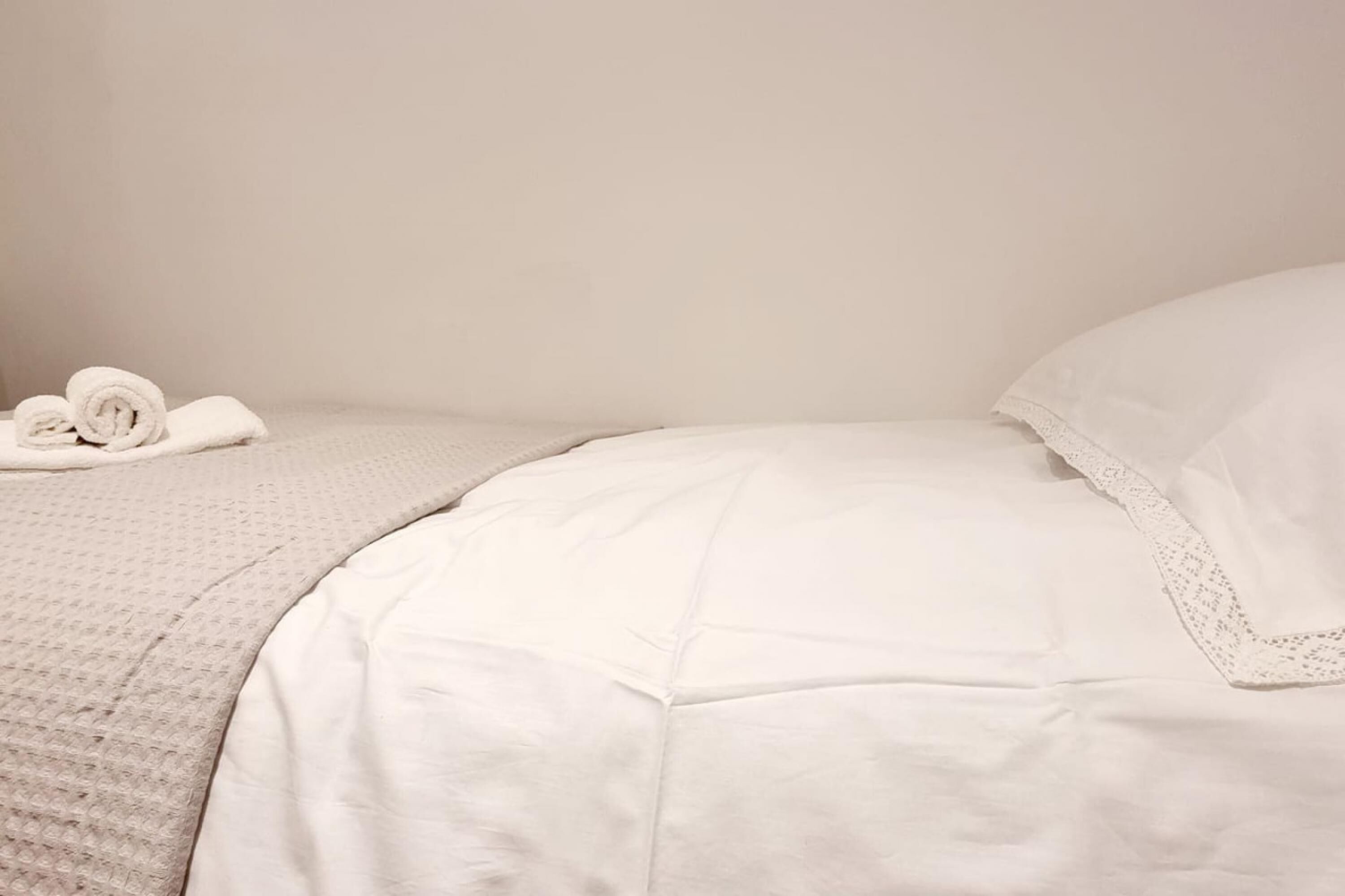 A neatly made bed with white linens and a textured blanket.