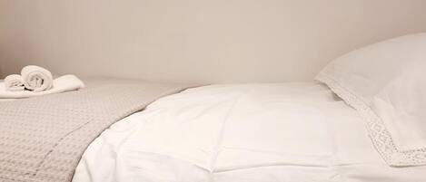 A neatly made bed with white linens and a textured blanket.