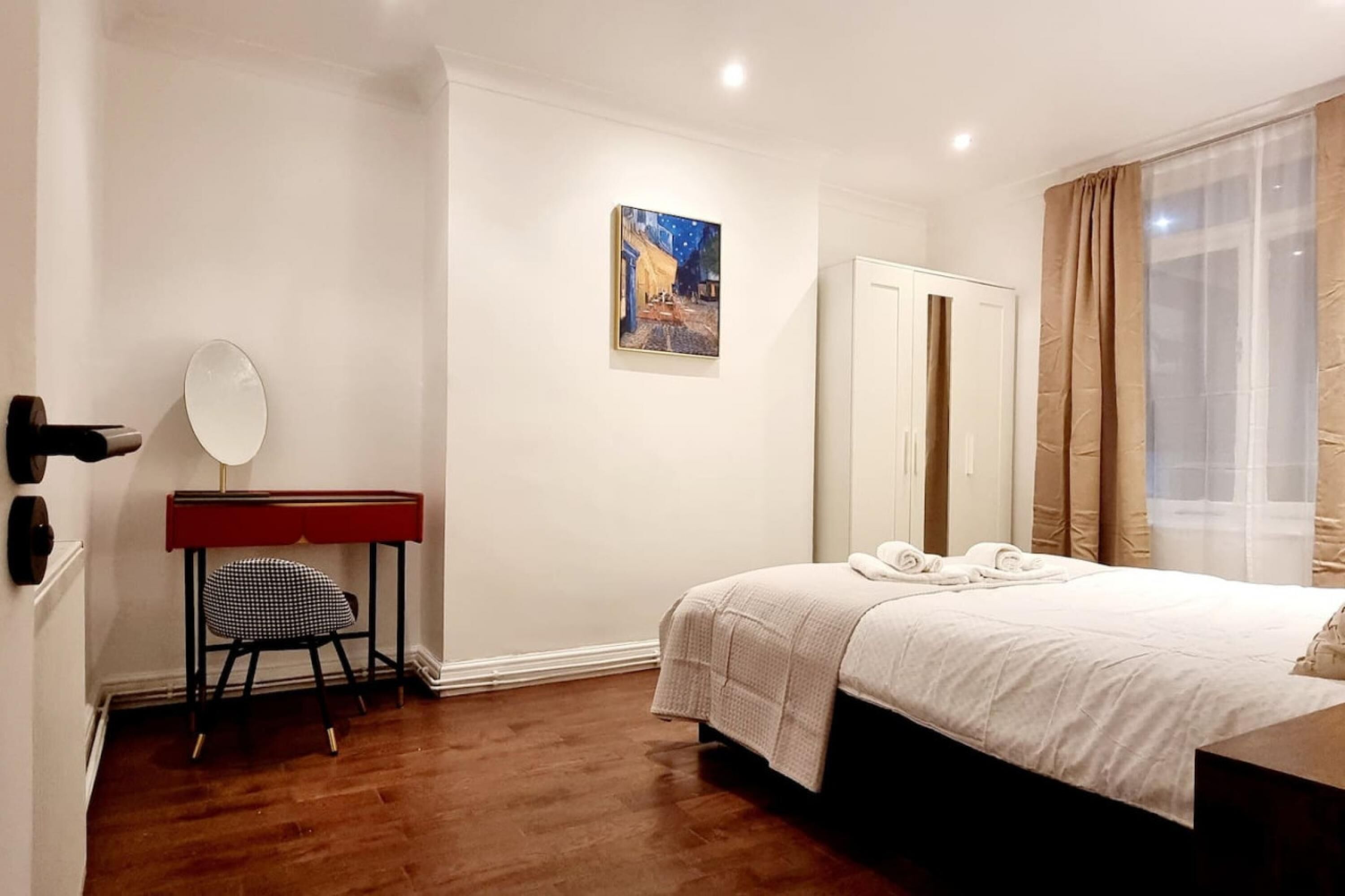 Une chambre d’hôtel comprenant un lit, un bureau avec une chaise, un miroir, un tableau accroché au mur et une armoire.