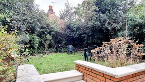A garden with steps leading to a brick wall, surrounded by various plants and trees. - Private Garden Flat Central London Air Conditioning (London)