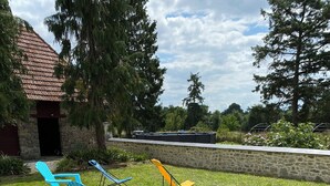A grassy outdoor area with two blue lounge chairs and one yellow folding chair.