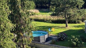 A backyard with a swimming pool, stone wall, and three chairs.