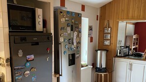 A kitchen with a refrigerator, microwave, and a water dispenser.