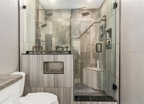 A modern bathroom with a glass shower enclosure, a vanity with a sink, and a toilet. - Gorgeous pool home in South Lakeland. Family and pet friendly! (Lakeland)