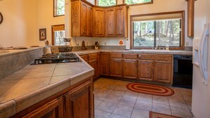 A kitchen with wooden cabinets, a gas stove, and a dishwasher. - Millville Chalet ~ Pool Access! (Camp Connell)