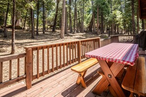 A wooden deck with a picnic table and bench, surrounded by a wooden fence, overlooking a forested area. - Millville Chalet ~ Pool Access! (Camp Connell)