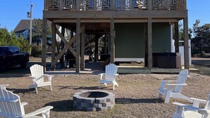 A two-story building with a balcony, outdoor seating area, and a fire pit. - “Sound Decision” Carova Beach Canal Front Home!! 4x4 Required (Corolla)