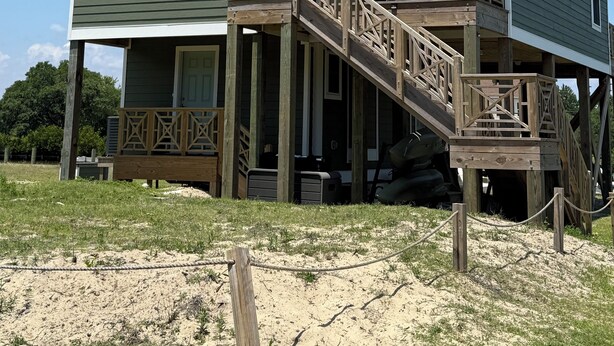 A two-story house with a balcony and a deck, featuring a logo and a number '509'. - “Sound Decision” Carova Beach Canal Front Home!! 4x4 Required (Corolla)