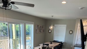 A spacious living area with a large window, a ceiling fan, and a dining table. - “Sound Decision” Carova Beach Canal Front Home!! 4x4 Required (Corolla)