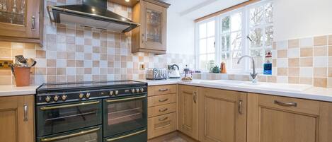 A kitchen with wooden cabinets, a black stove, and a window providing natural light.