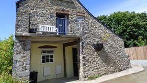 A stone building with a balcony, a door, and a window.