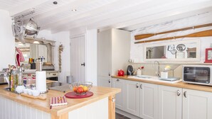 A kitchen with a wooden countertop, white cabinets, and a microwave. There is a fruit bowl on the counter and various kitchen utensils. - 1 Penally Boathouse Mews, Holiday Cottage St Dogmaels, Sleeps 4, 2 bedrooms,  bathrooms (Cardigan)