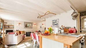 A cozy kitchen with a wooden island, stone flooring, and a rustic decor including a fireplace and a wall-mounted fish painting. - 1 Penally Boathouse Mews, Holiday Cottage St Dogmaels, Sleeps 4, 2 bedrooms,  bathrooms (Cardigan)