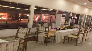 A banquet hall with tables set for dining, chairs, and a stage with lighting. - Aravalli Golf Course (Faridabad)