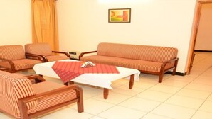 A living room with striped sofas and armchairs, a coffee table, and a painting on the wall. - Aravalli Golf Course (Faridabad)
