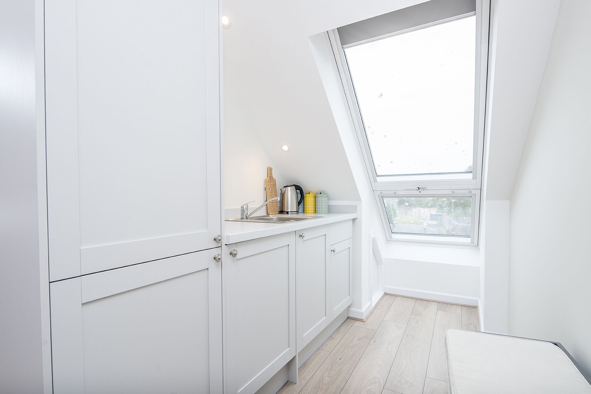 A modern kitchen with white cabinetry, a skylight, and a view of the city.