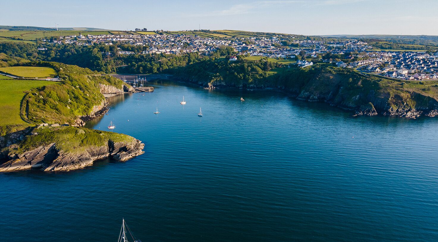An aerial view of a coastal town with a harbor, boats, and a lighthouse.