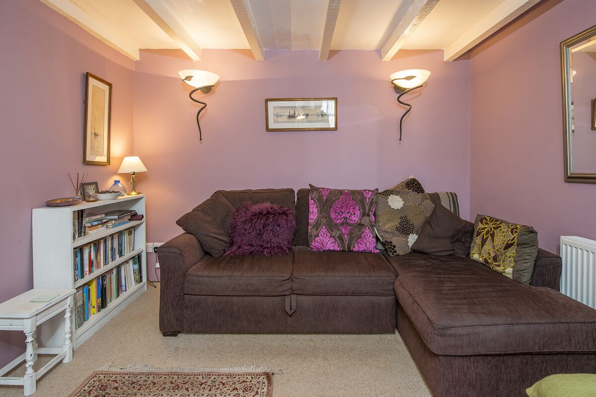 A cozy living room with a brown sofa, a white side table, a bookshelf, and two wall-mounted lamps.