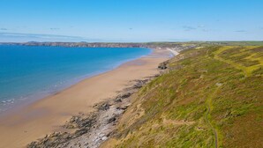 A coastal landscape with a sandy beach, grassy hills, and a clear blue sea. - 19 St Brides Bay, Holiday Apartment Broad Haven, Sleeps 6, 3 bedrooms,  bathrooms (HAVERFORDWEST)