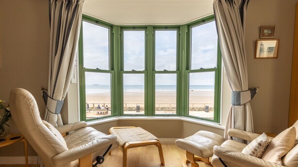 A room with a bay window overlooking a beach, featuring two leather chairs and a wooden table. - 19 St Brides Bay, Holiday Apartment Broad Haven, Sleeps 6, 3 bedrooms,  bathrooms (HAVERFORDWEST)