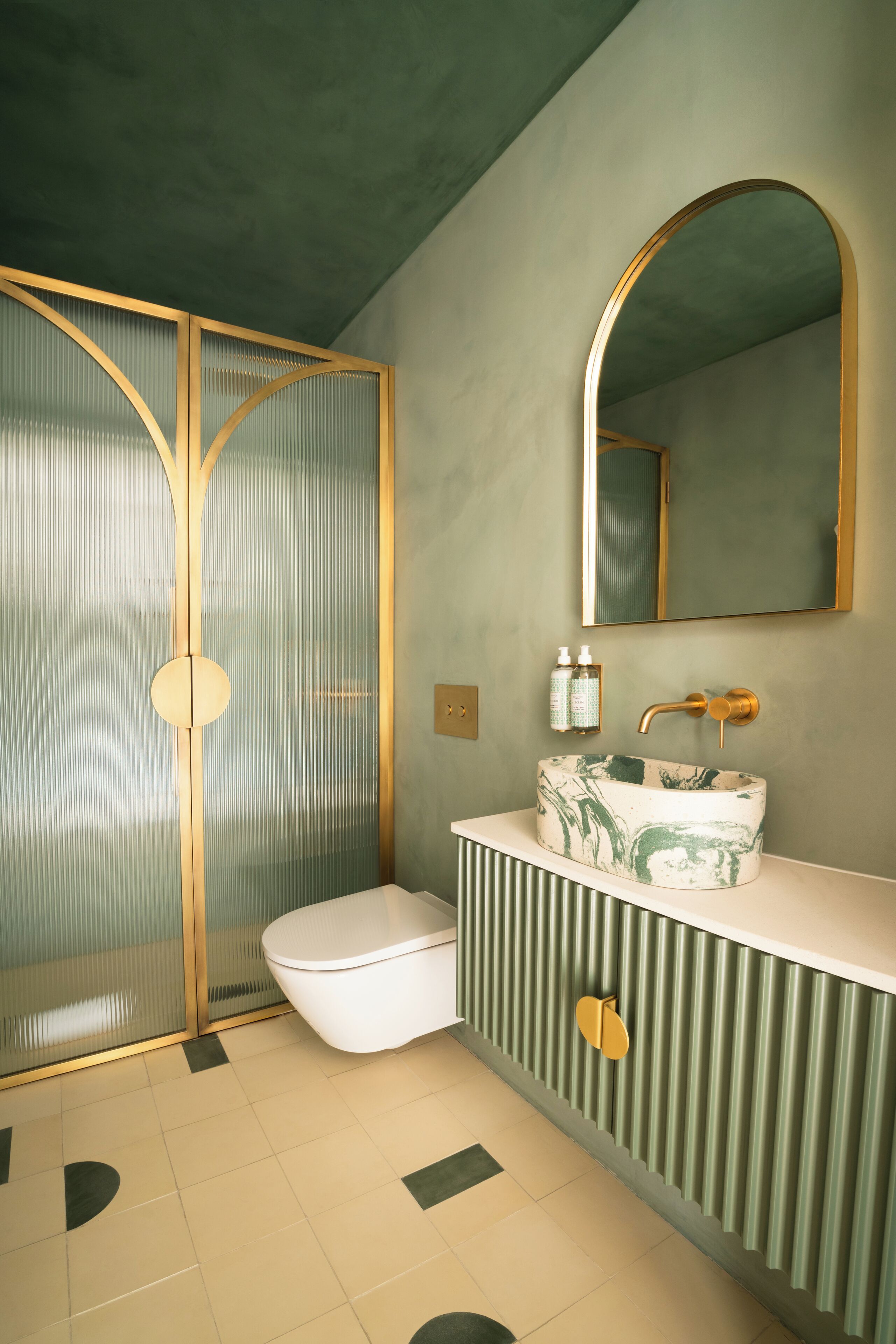 A bathroom with a white toilet, a marble sink, and a large mirror.