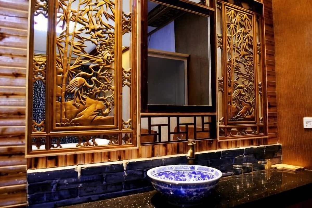 A bathroom with a large mirror, a blue ceramic sink, and intricate wooden paneling.