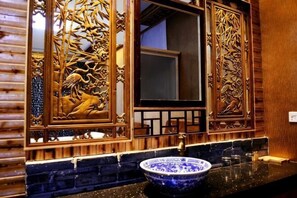 Une salle de bain dotée d’un grand miroir, d’un lavabo en céramique bleue et de panneaux de bois aux motifs complexes.