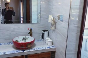 Ein Badezimmer mit Marmorwaschbecken, Spiegel, Telefon und Kaffeemaschine.