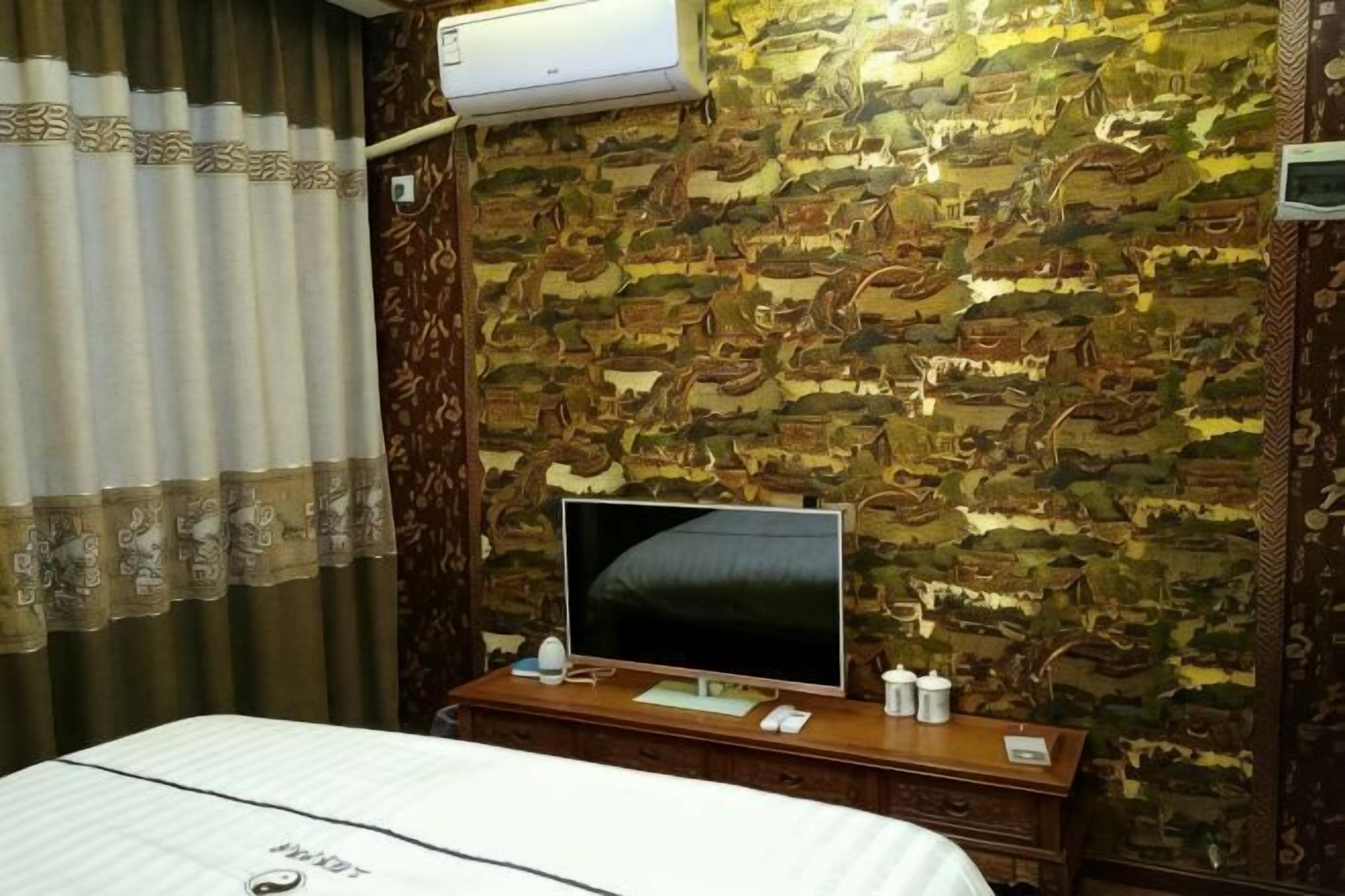 Habitación de hotel con papel tapiz estampado, un televisor de pantalla plana sobre una cómoda de madera y una cama con cubrecama blanco.