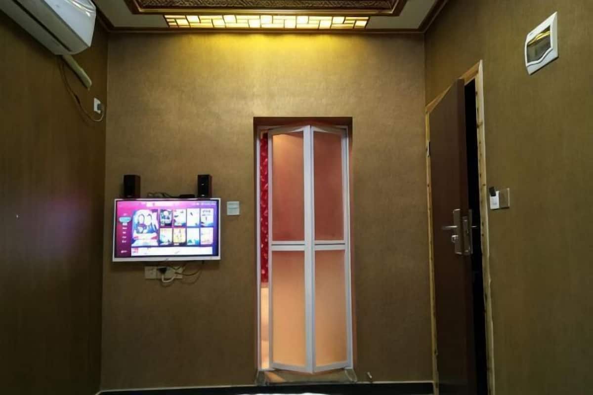 Une chambre d’hôtel équipée d’un téléviseur fixé au mur, d’une porte et d’un luminaire au plafond.
