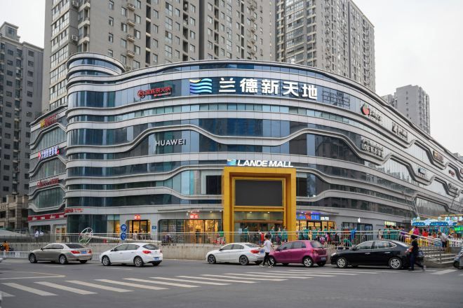 A multi-story commercial building with a curved facade, featuring prominent signage for 'Huawei' and 'Lande Mall'.